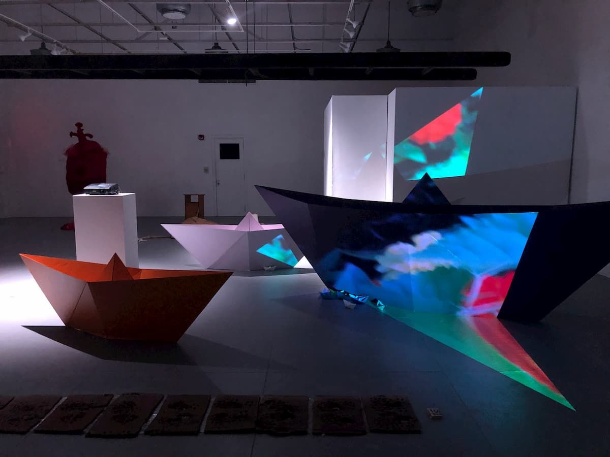 Three large boats that look like they were made from large sheets of paper.