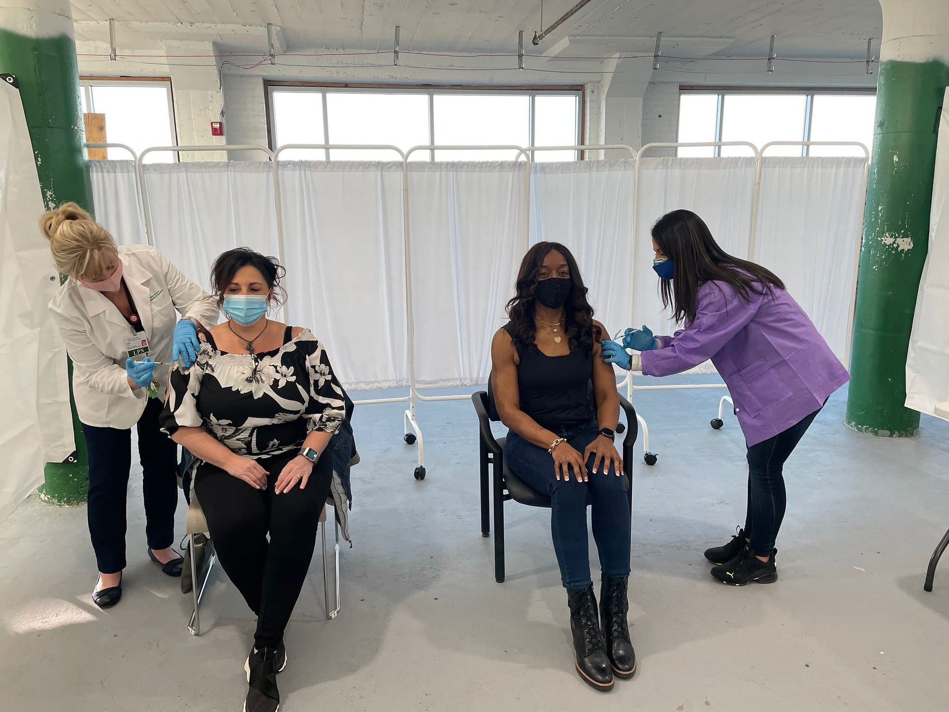 Two women receive shots in their arms.