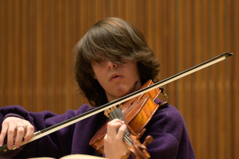 A male plays a violin.
