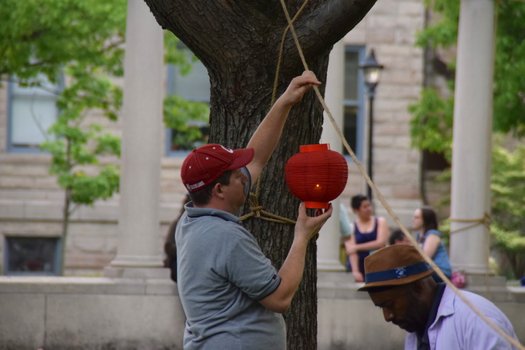 A man holds up a lanter and looks at the lit candle inside.